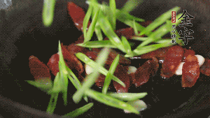 先后下香腸片、四季豆絲均勻翻炒，加適量清水燜煮一下。